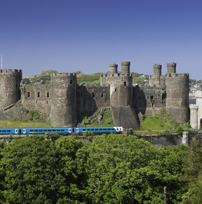Train going passed Conwy Castle on a sunny day.