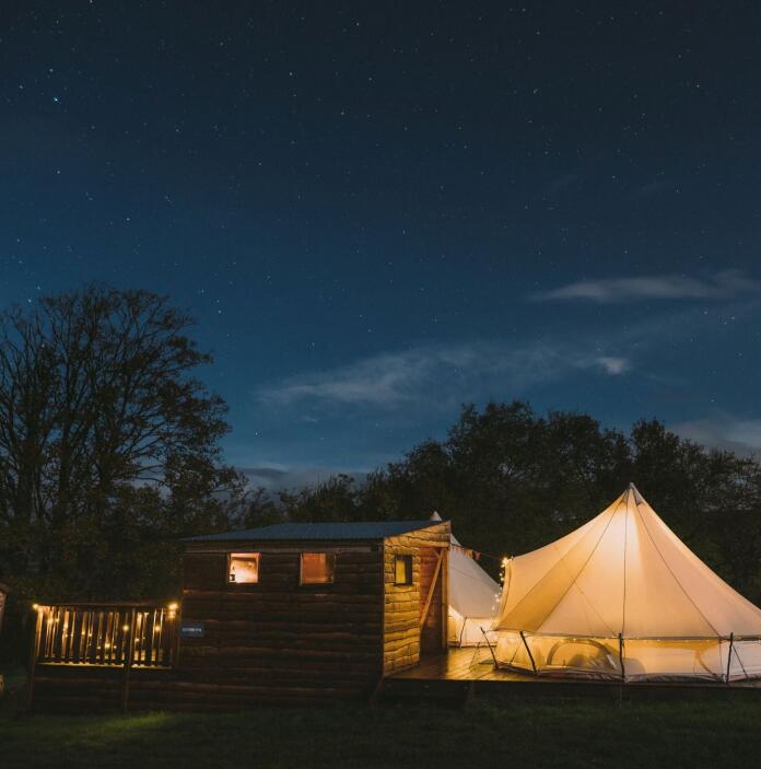 Bell tents in the evening with lights on.