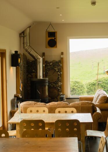 Interior of an eco lodge with a coal fire, sofas and views out the hills.