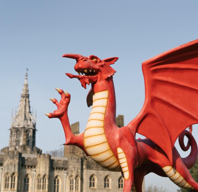 A statue of a Welsh dragon with a castle in the background.