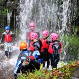 A group of people under a waterfall wearing safety gear.