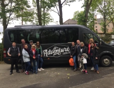 Group of people standing outside mini bus.