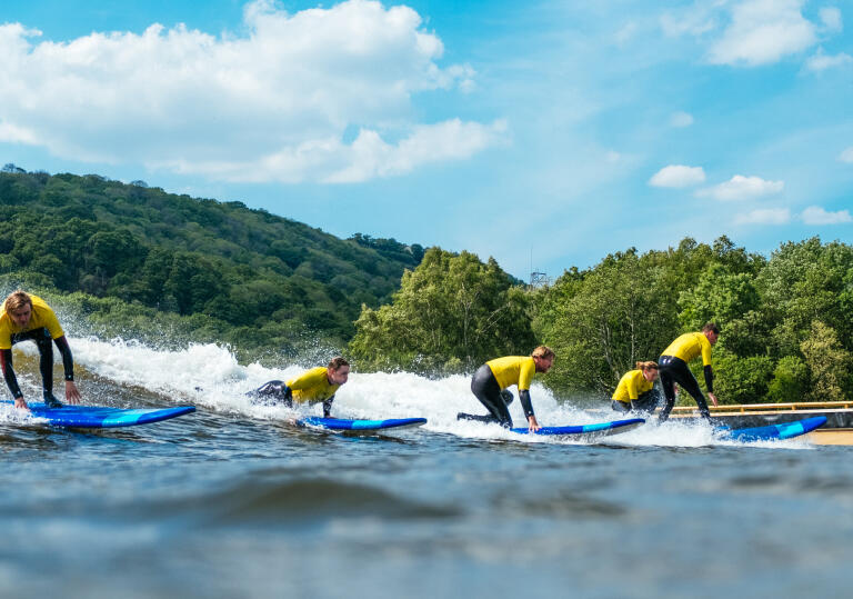 Surfers riding the waves on an inland surf lagoon.