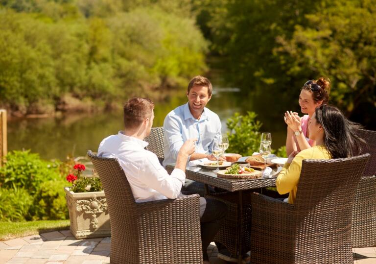 A group of people dining alfresco near a lakeside. 