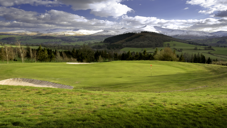Dramatic mountains seen from a putting green.