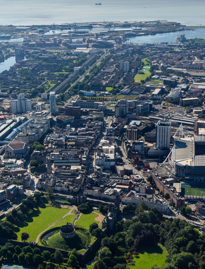 Aerial view of Cardiff city centre including a big arena, park and river.
