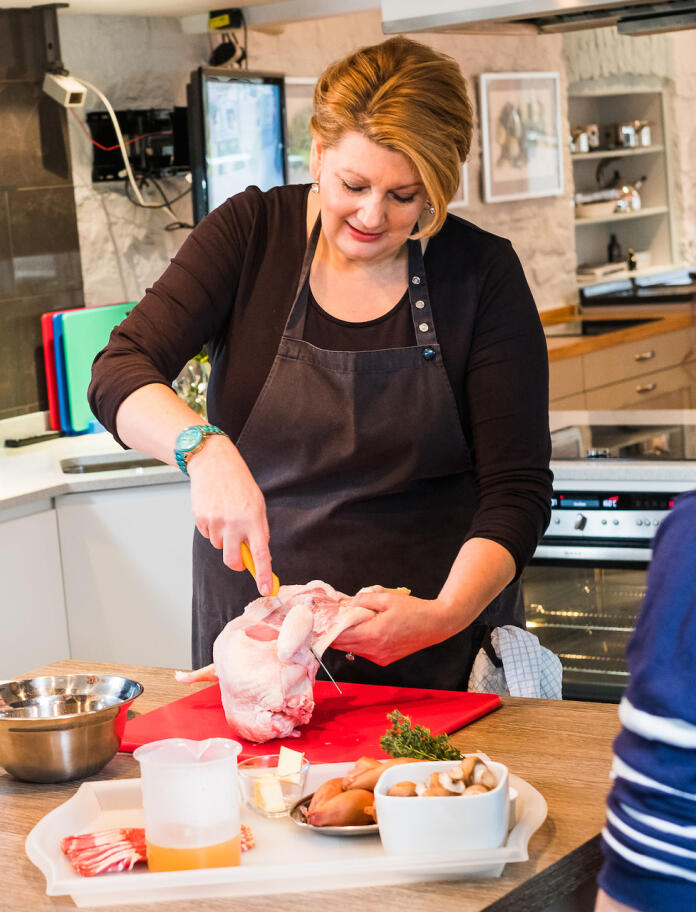 Angela Gray demonstrating how to fillet a chicken at her cookery school.