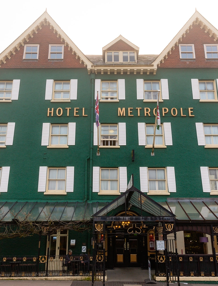 Front view of a large, green painted hotel.