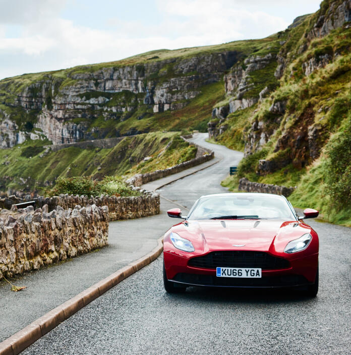 An Aston Martin driving along a coast road.