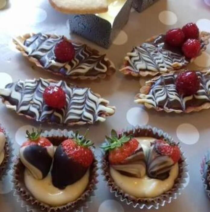 A selection of cakes and chocolates decorated with berries.