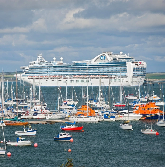 Cruise ship in the sea with smaller boats also in view. 