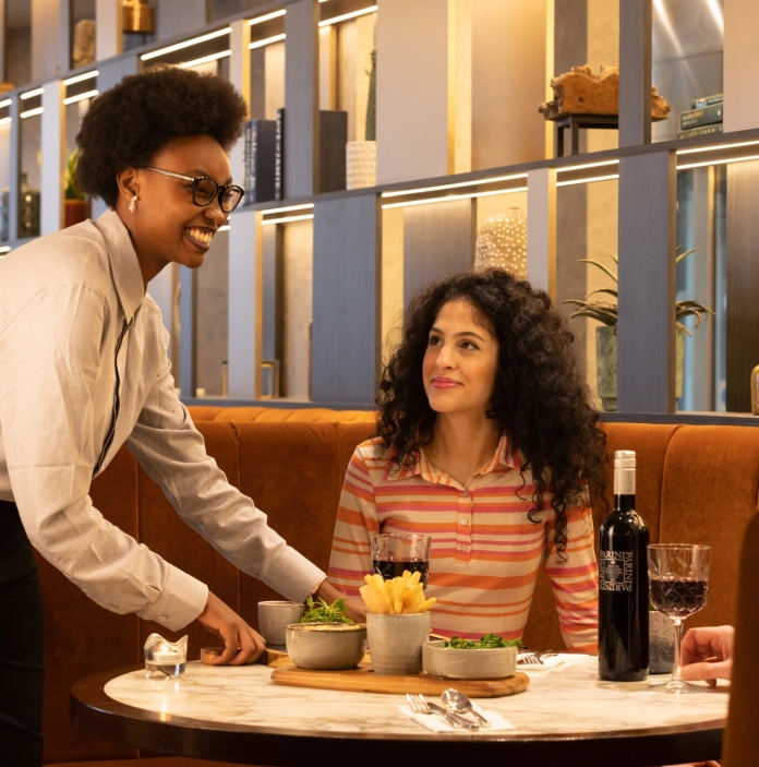 Waitress serving a couple some food at a table.