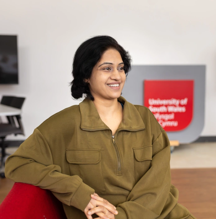 Person seated in a modern university interior with South Wales Business School signage.