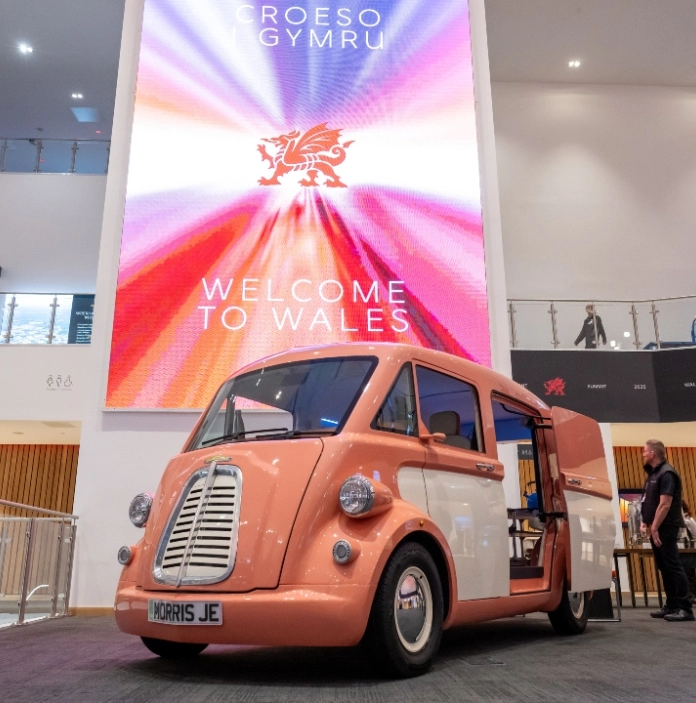 Retro van showcased inside a modern venue with a large ‘Welcome to Wales’ digital screen.