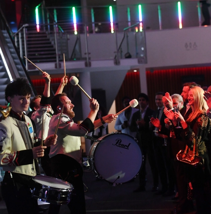 Live drum performance as guests applaud at a gala dinner in a modern event venue