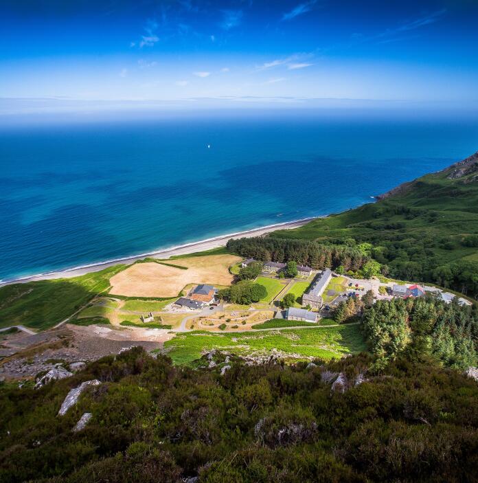 Aerial shot of Nant Gwrtheyrn surrounded by green landscape and the sea.