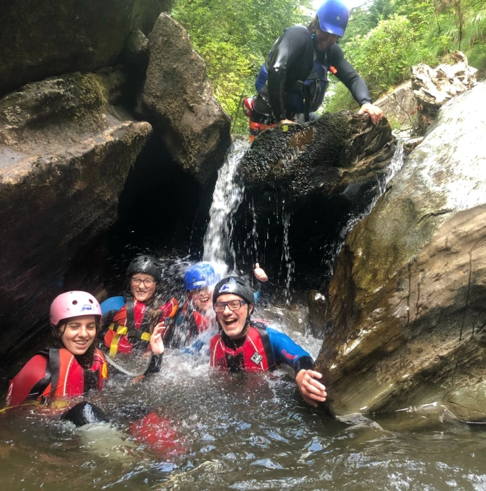 group of adults in river laughing under rocks