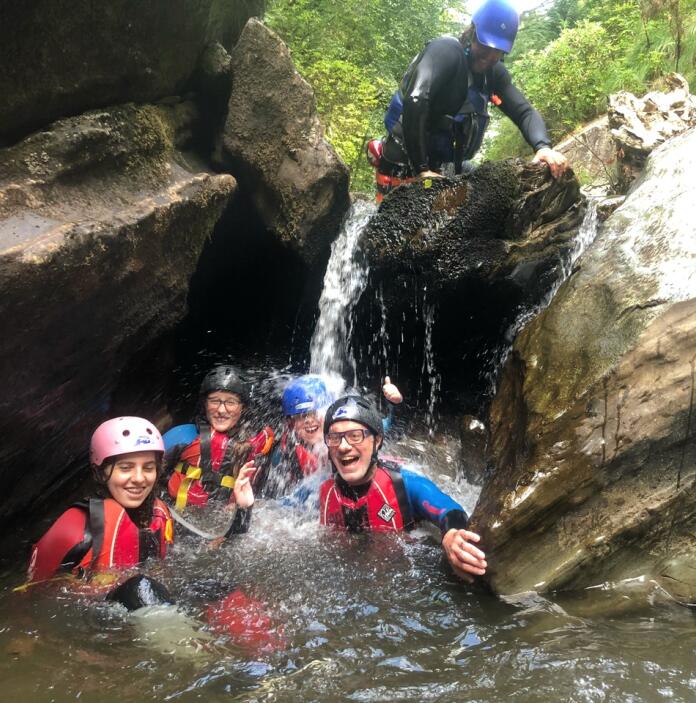 group of adults in river laughing under rocks 