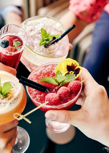 A variety of colourful refreshing drinks adorned with fruit and mint.