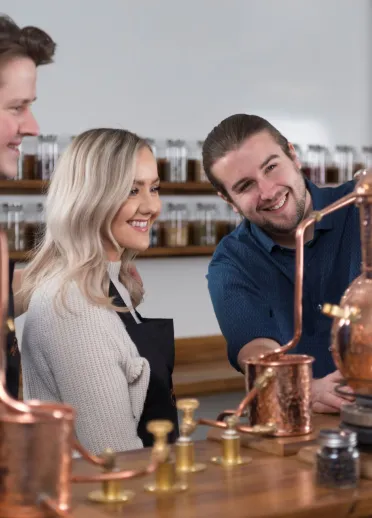 A man showing a couple around a distillery.