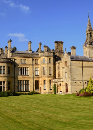 External shot of a beautiful historic hotel framed with blue skies and manicured lawns.