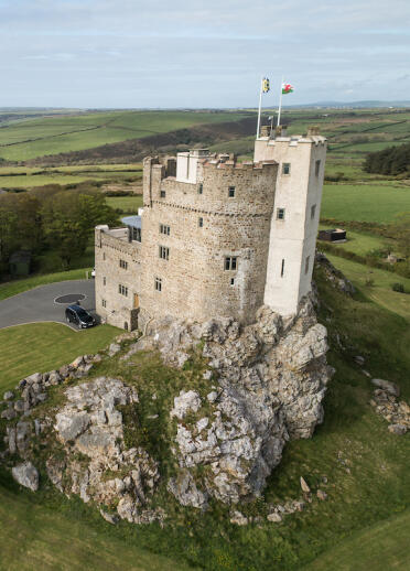 A castle hotel on a hill with views of the sea beyond.