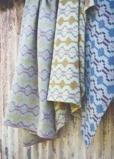 Colourful Welsh wool blankets hanging on the side of a hut.