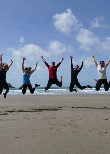 Group of people jumping on a beach.