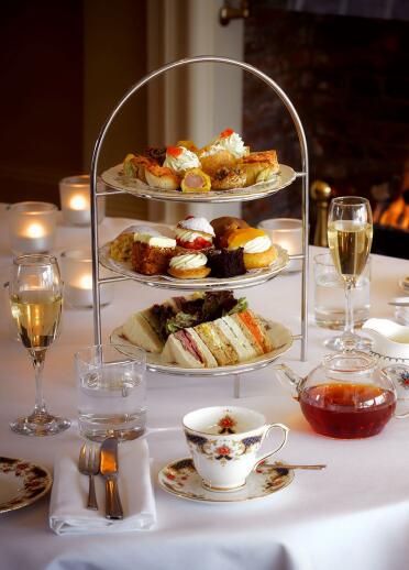 Afternoon tea set up on a table with a roaring fire in the background.
