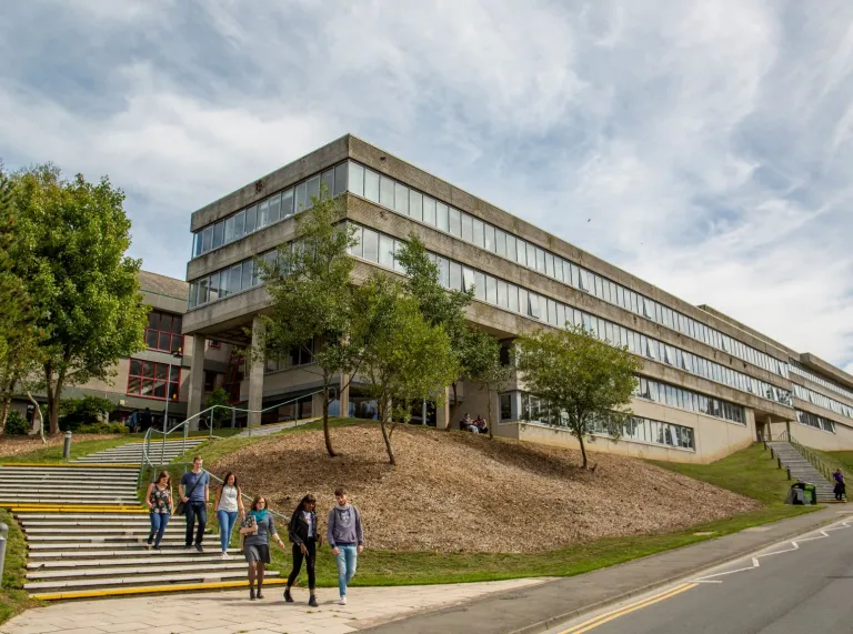 External view of a university building with students walking down the steps.