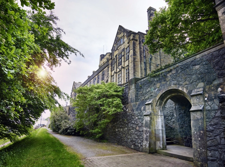 An external view of a university alongside a path lined with greenery.