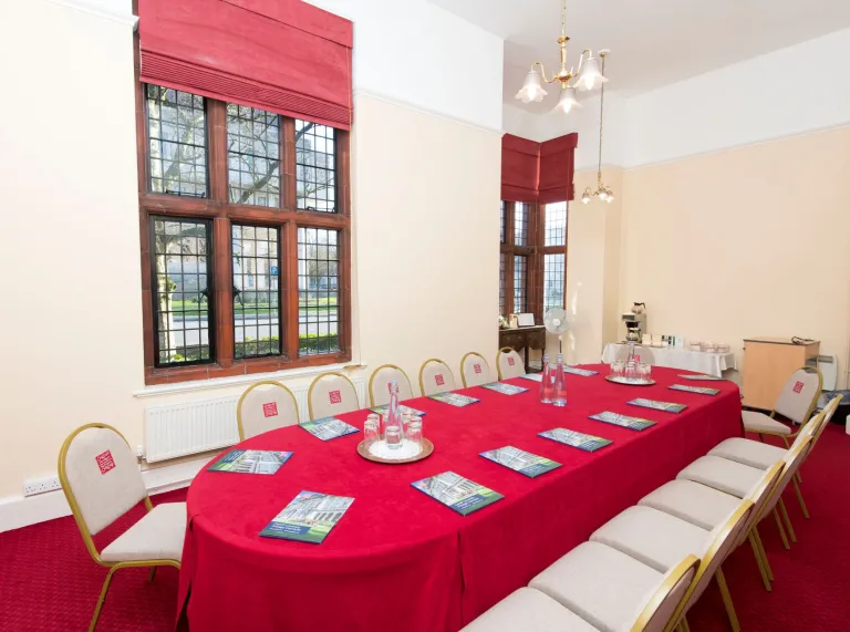 A board room style meeting room with red and cream decor and catering facilities.
