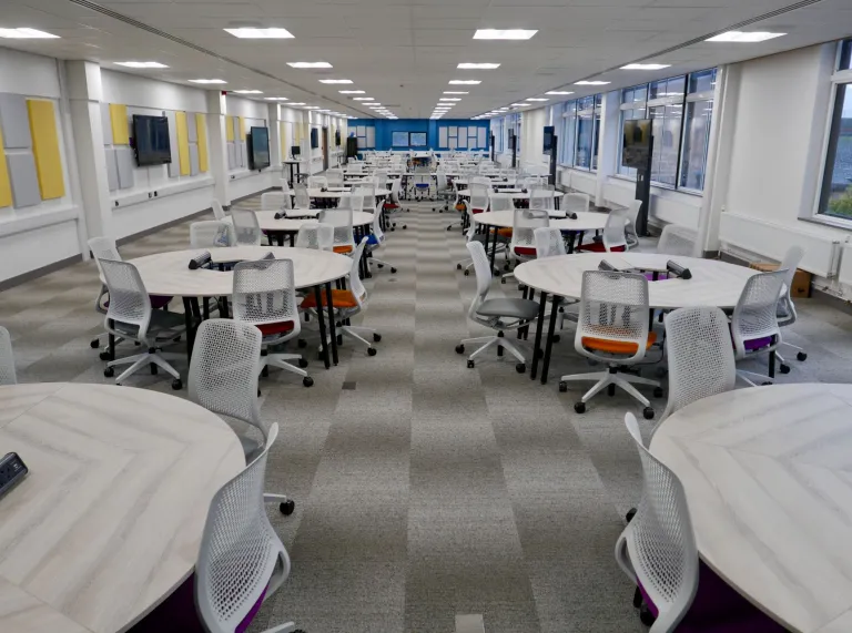 A long meeting room with round tables at a university.