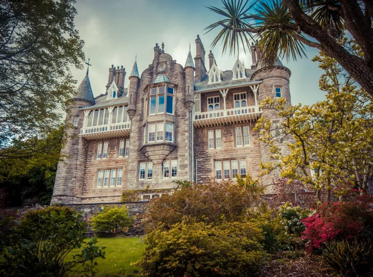 An external view of a grand chateau framed with trees and foliage.