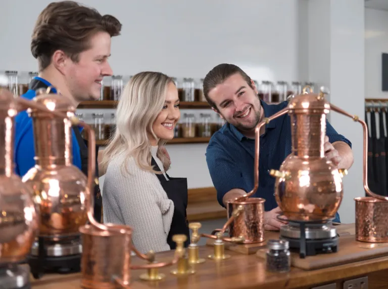 A man showing a couple around a distillery.