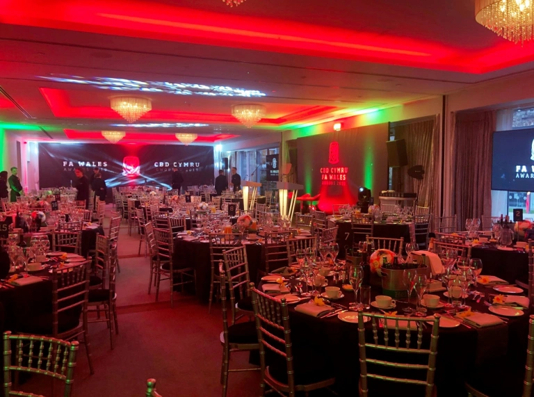 Circular dining tables in a meeting space lit with colourful lights.