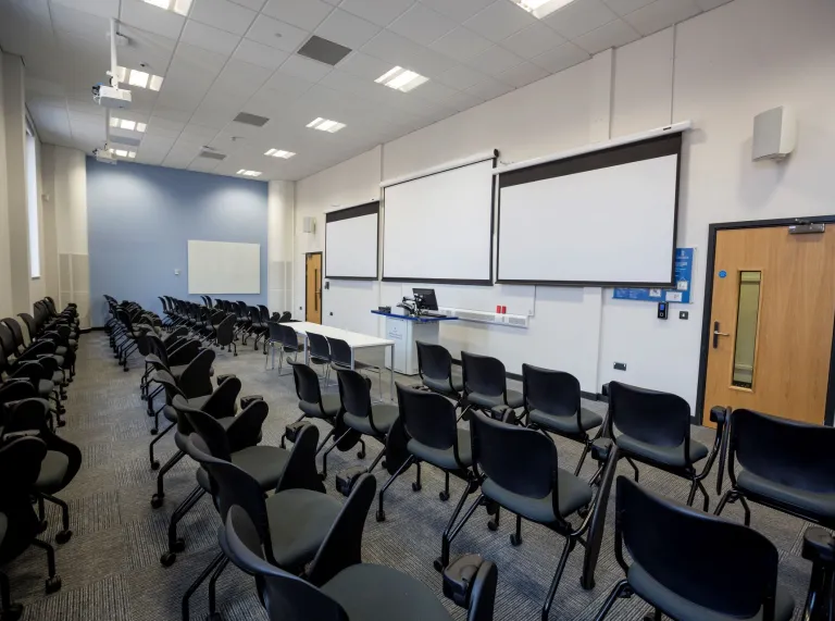 Chairs in a breakout meeting room facing projector screens.