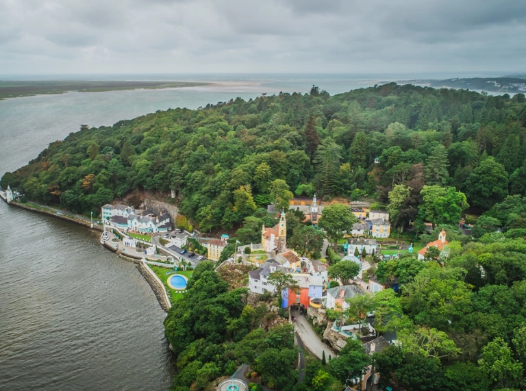 Aerial shot of a hotel and italiante village on the cove of a coastline.