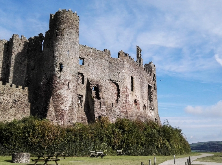 External shot of a castle, with people walking up the path next to green lawns.