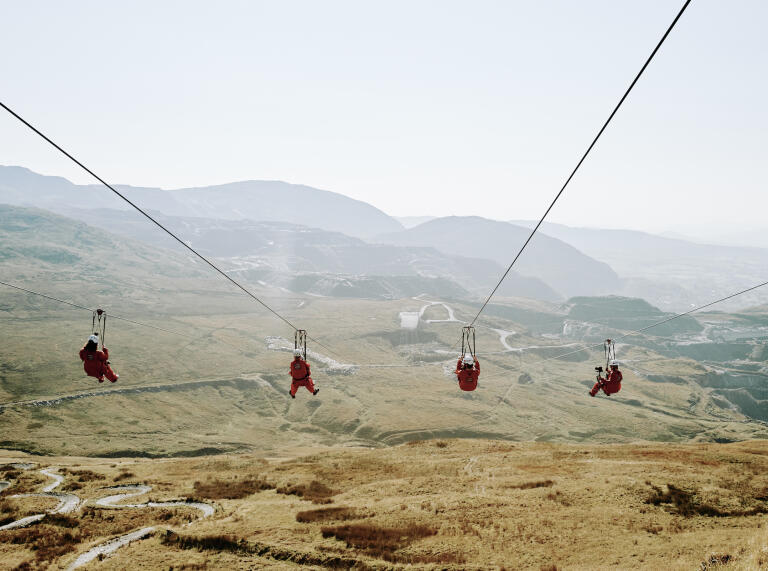 Four people on a zipwire with views of a former quarry below.