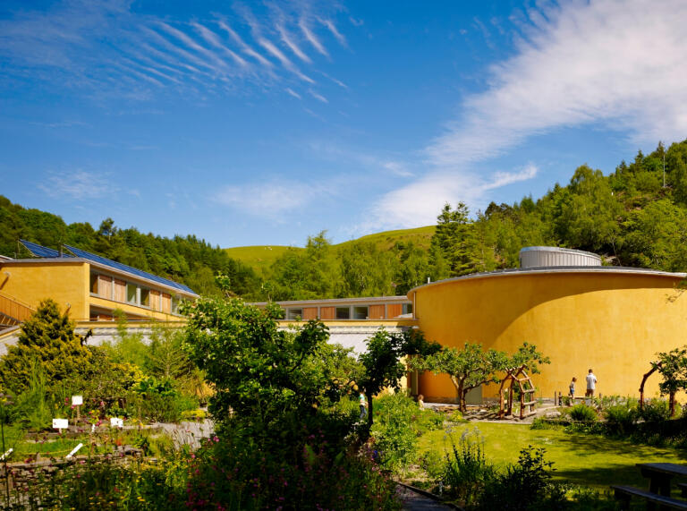 Buildings at an eco centre surrounded by greenery on a sunny day.
