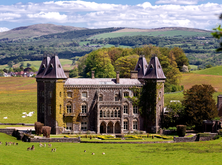A grand house covered in Ivy with views of the countryside beyond.