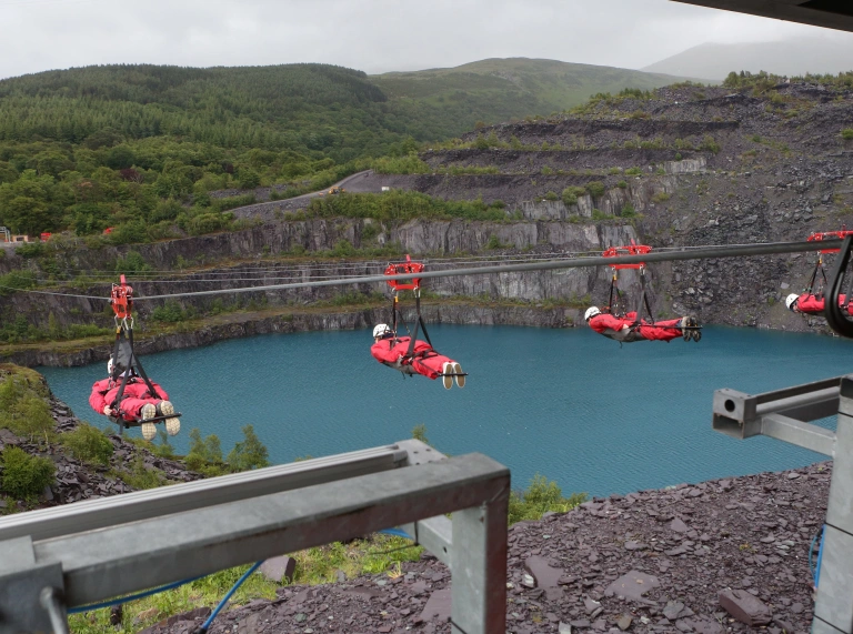 Zip liners travelling down a zip wire over a reservoir.
