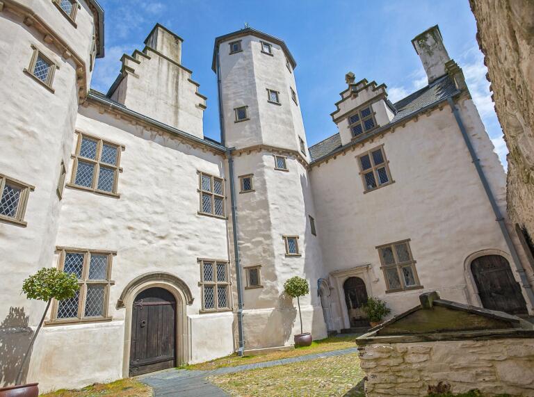 Looking up from a courtyard to an Elizabethan town house towers and windows.