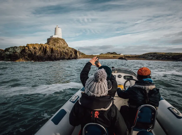 Group of people in Rib Ride boat passign Llandwyn Island and taking a photo.