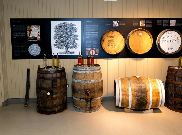 Whisky barrels with bottles of Whisky and information panels behind.