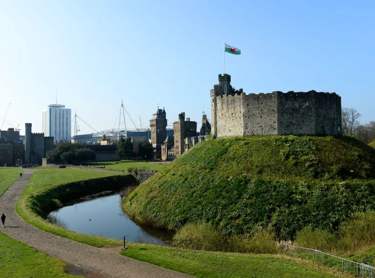 Cardiff castle and the moat with the principality stadium in the background.