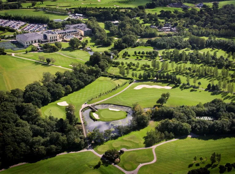 Looking down on the grounds of the resort, green grass and golf course with trees and hotel in the far background.