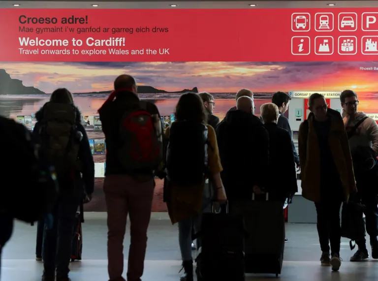 People walking toward a welcome sign into arrivals at Cardiff airport.