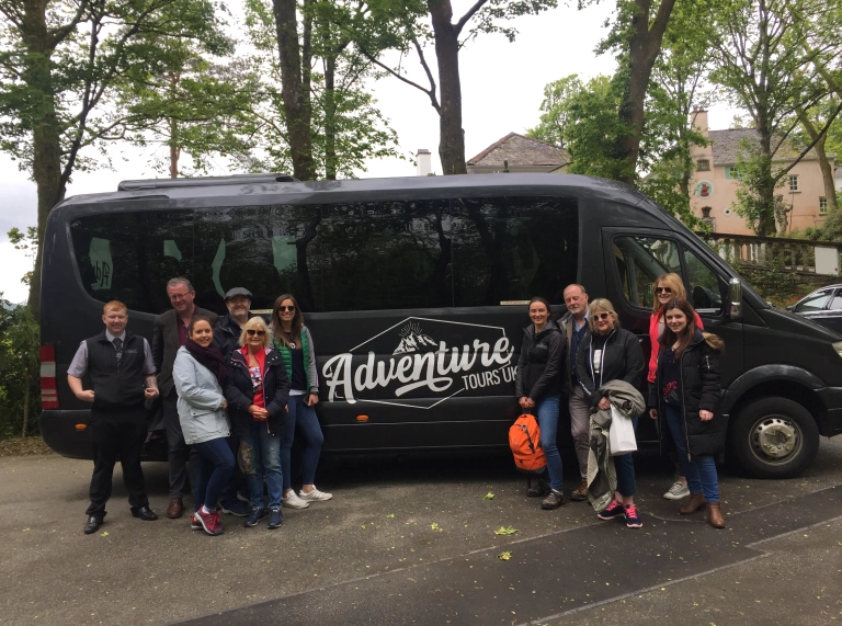 Group of people standing outside mini bus.